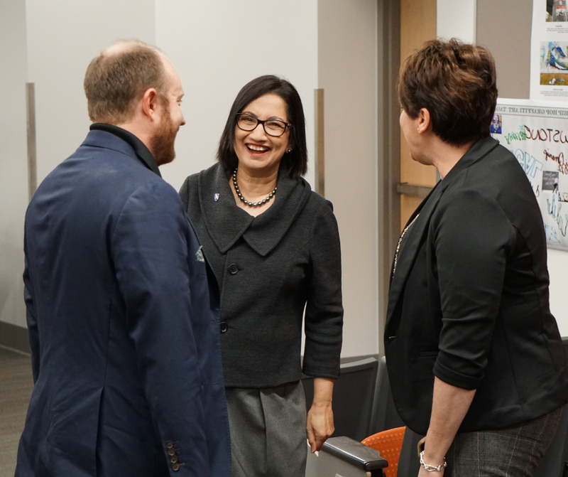 Woman laughing and smiling while standing beside a man and woman.